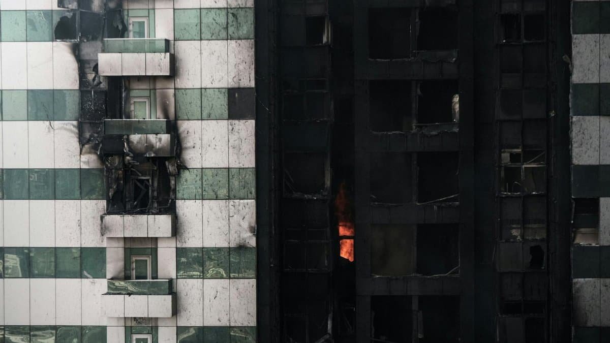 A close-up view of a scorched building facade with visible fire damage and flames.