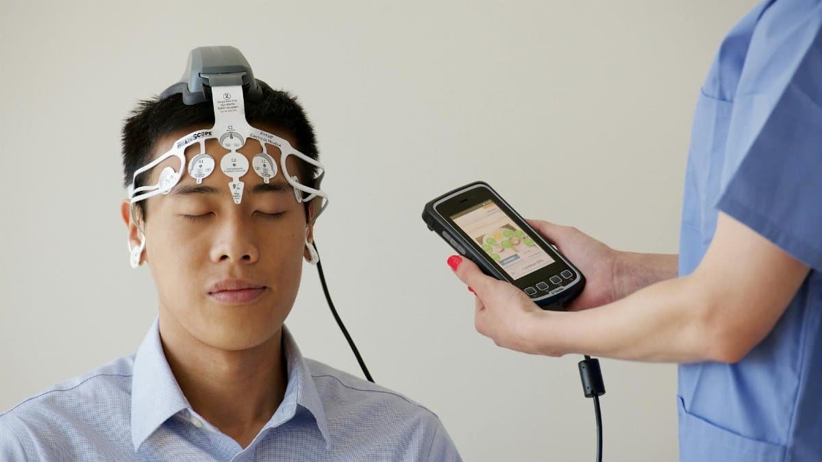 Healthcare professional conducting an EEG examination using a Brainscope device on a male patient.