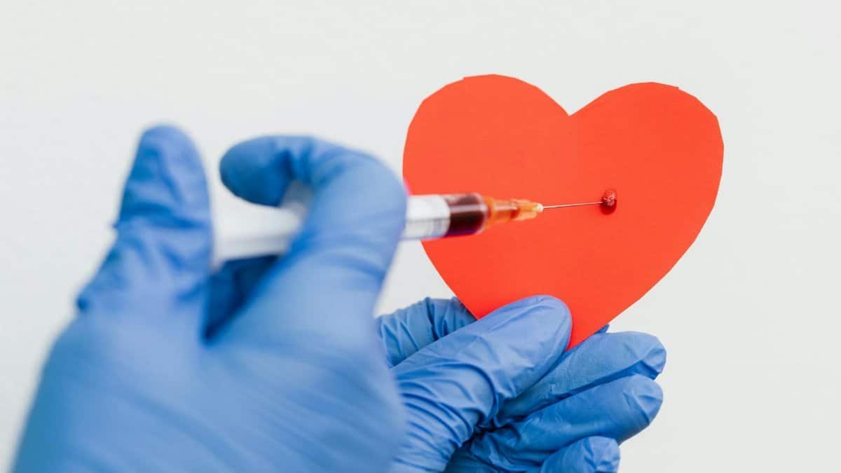 A conceptual image of a syringe injecting a red paper heart held by gloved hands, symbolizing health or love.