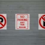 Red no parking signs on a gray wall in San Francisco, California.