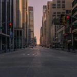 Empty New York City street at sunset with towering skyscrapers and soft glowing light.
