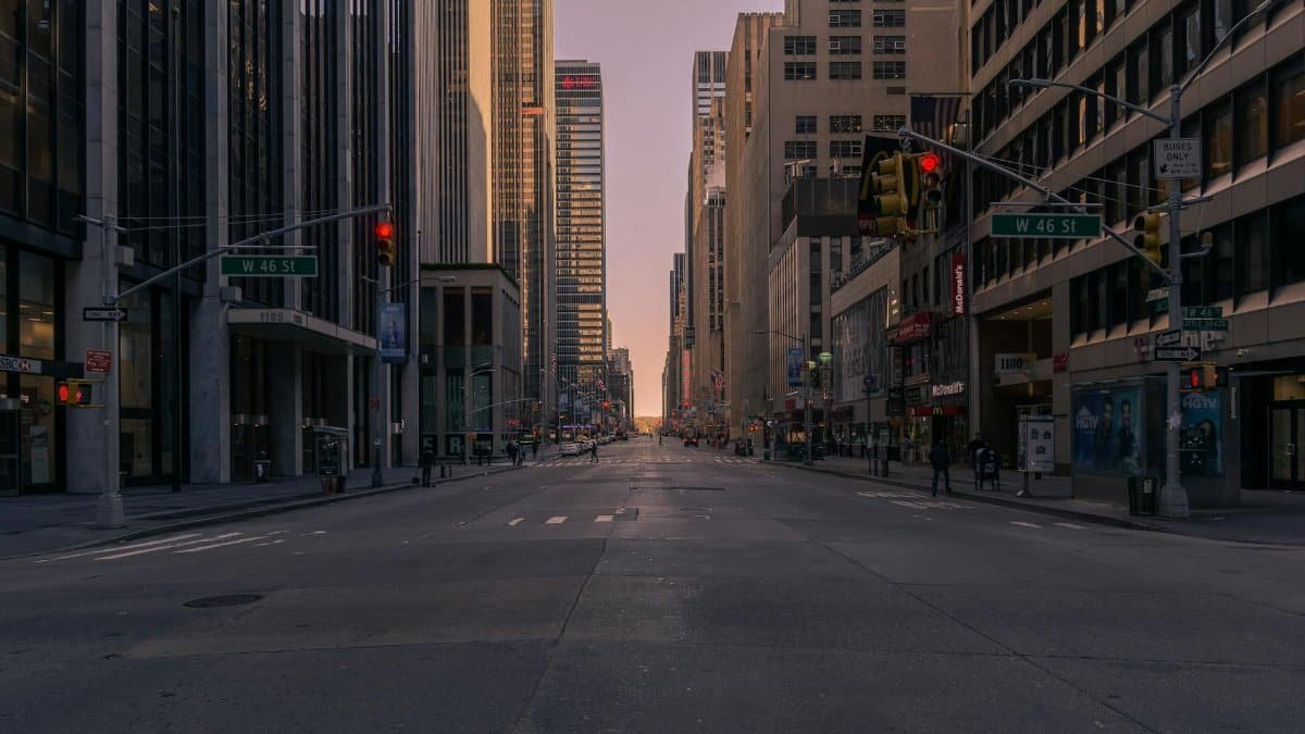 Empty New York City street at sunset with towering skyscrapers and soft glowing light.