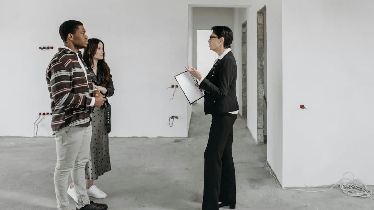 Real estate agent showing a house to a couple in a newly built home interior.