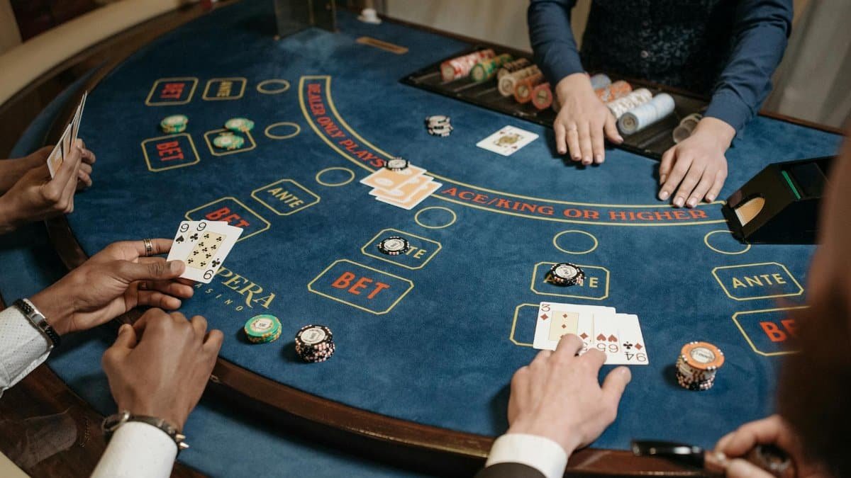 People playing a lively card game at a casino table with chips and a dealer.