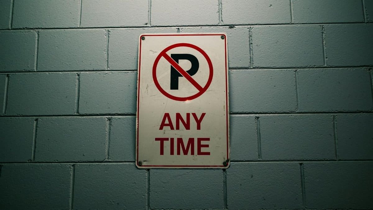 No parking sign against a gray brick wall, emphasizing traffic regulations.