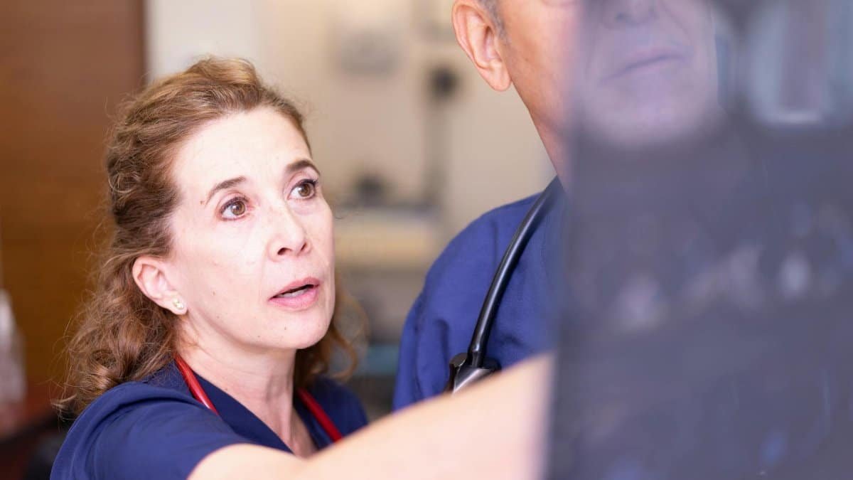 Doctors in scrubs examining an X-ray in a clinical setting for diagnosis.