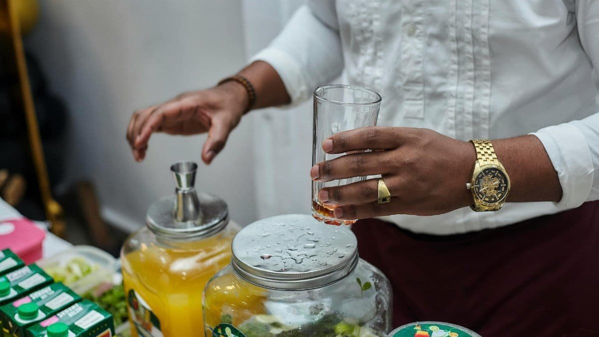 A bartender mixes drinks with fresh ingredients and juice indoors, showcasing beverage preparation.