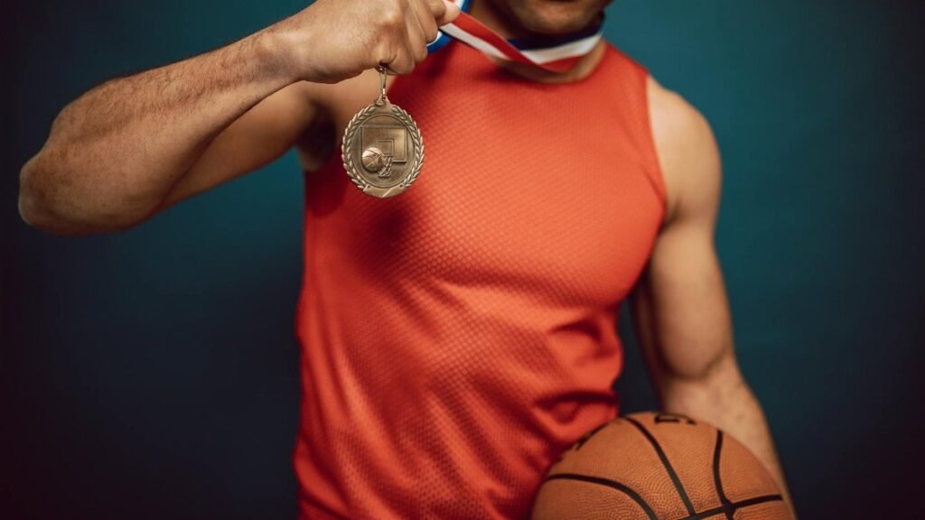 Man holding a medal and basketball, showcasing achievement in sports.