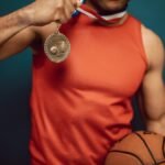 Man holding a medal and basketball, showcasing achievement in sports.