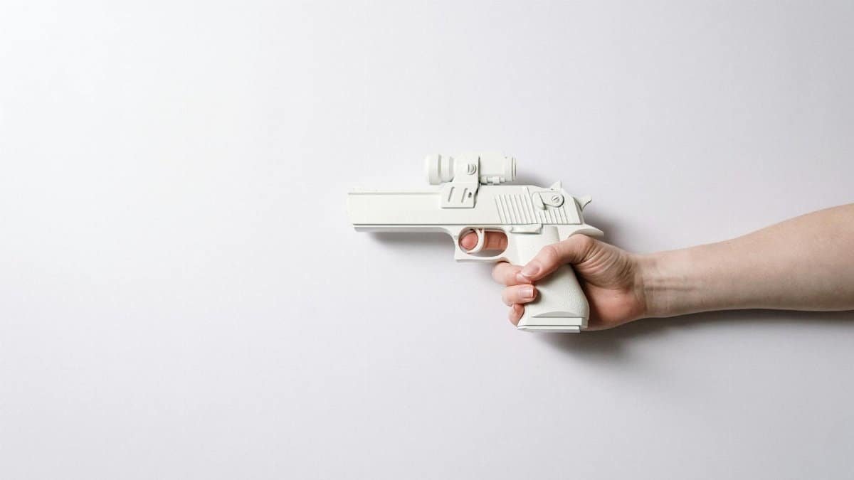 A minimalist shot featuring a white toy gun being held in a human hand, isolated on a plain background.