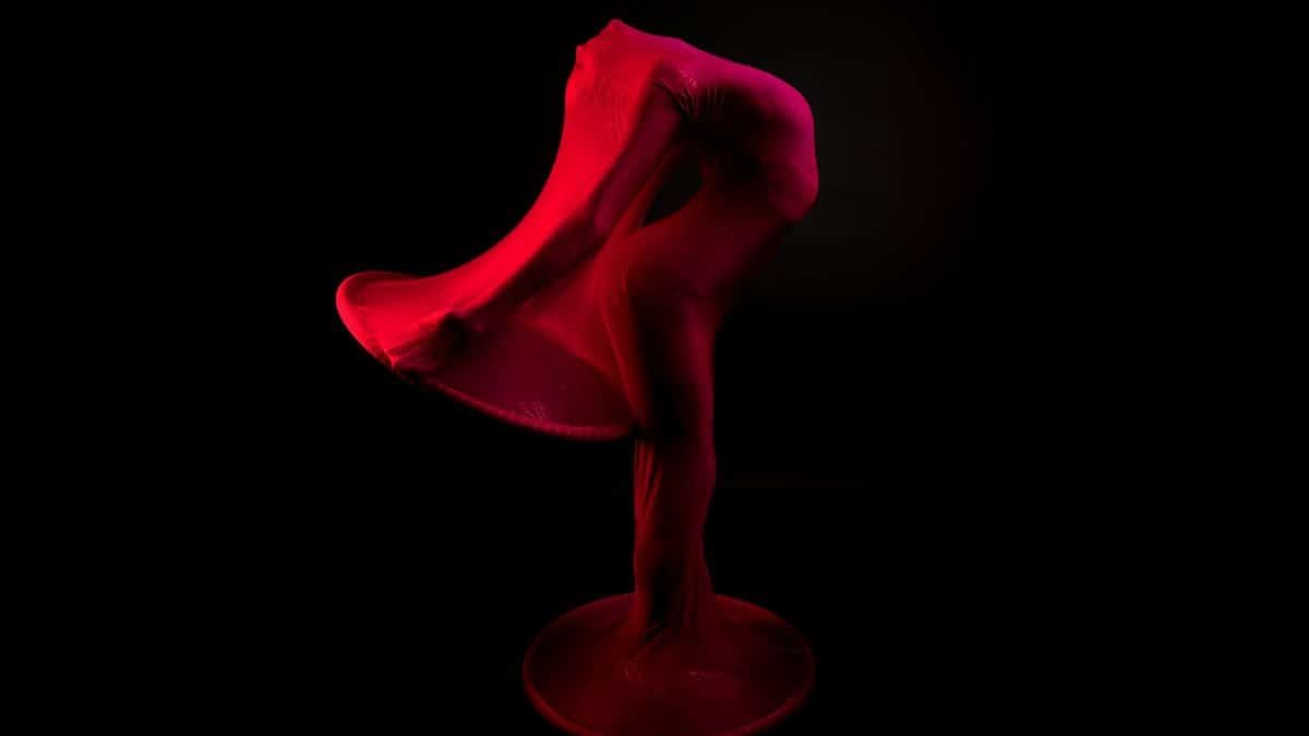 Abstract image of a dancer wrapped in red fabric, creating a dynamic artistic pose.