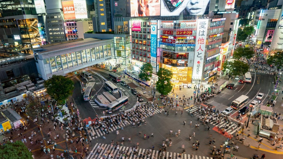 Shibuya Scramble Crossing in Tokyo teems with life, illuminated by vibrant city lights at night.