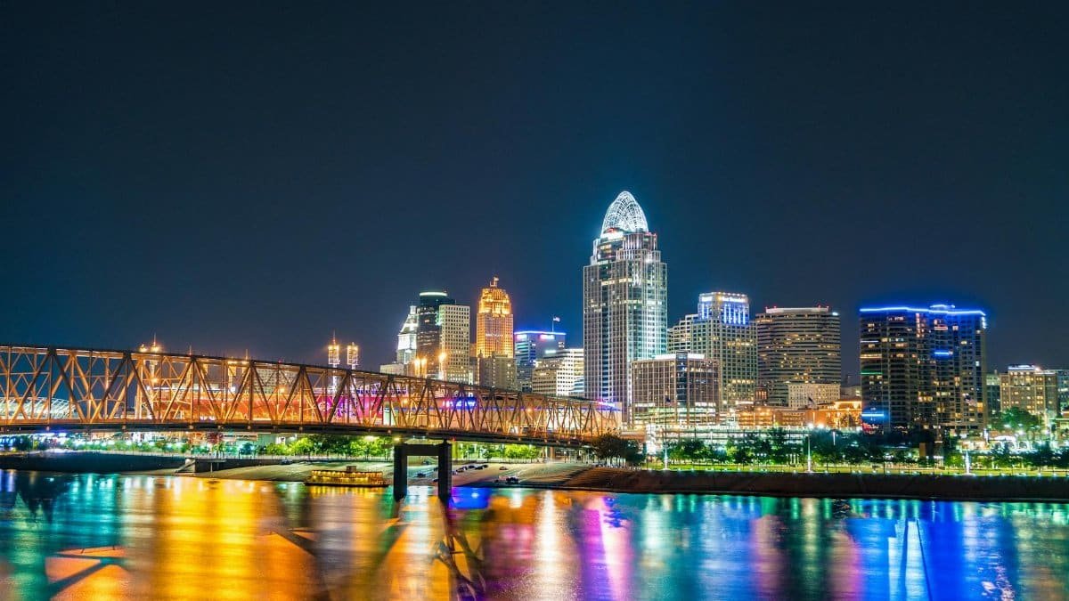 Captivating view of Cincinnati skyline with bridge reflections on Ohio River at night.