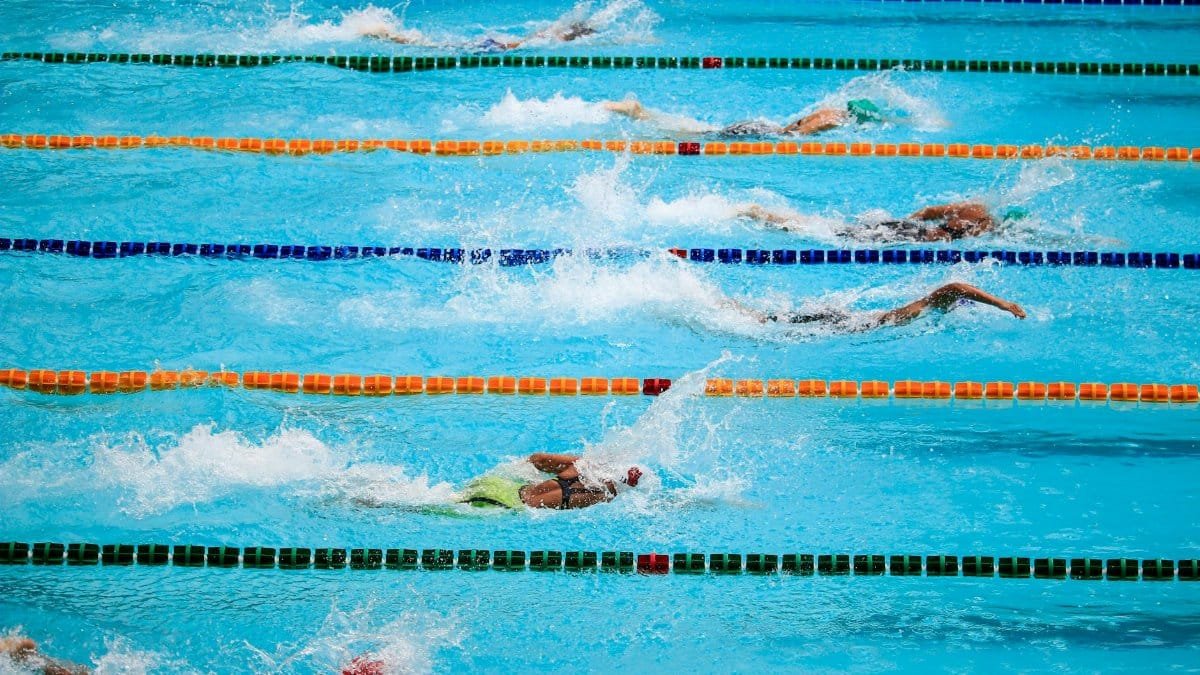 Swimmers compete in an outdoor pool race, showcasing athleticism and sportsmanship.