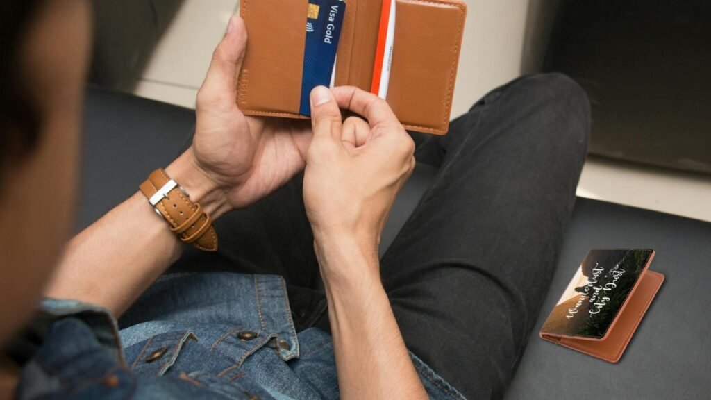 Over-the-shoulder view of a person holding a leather wallet displaying credit cards.