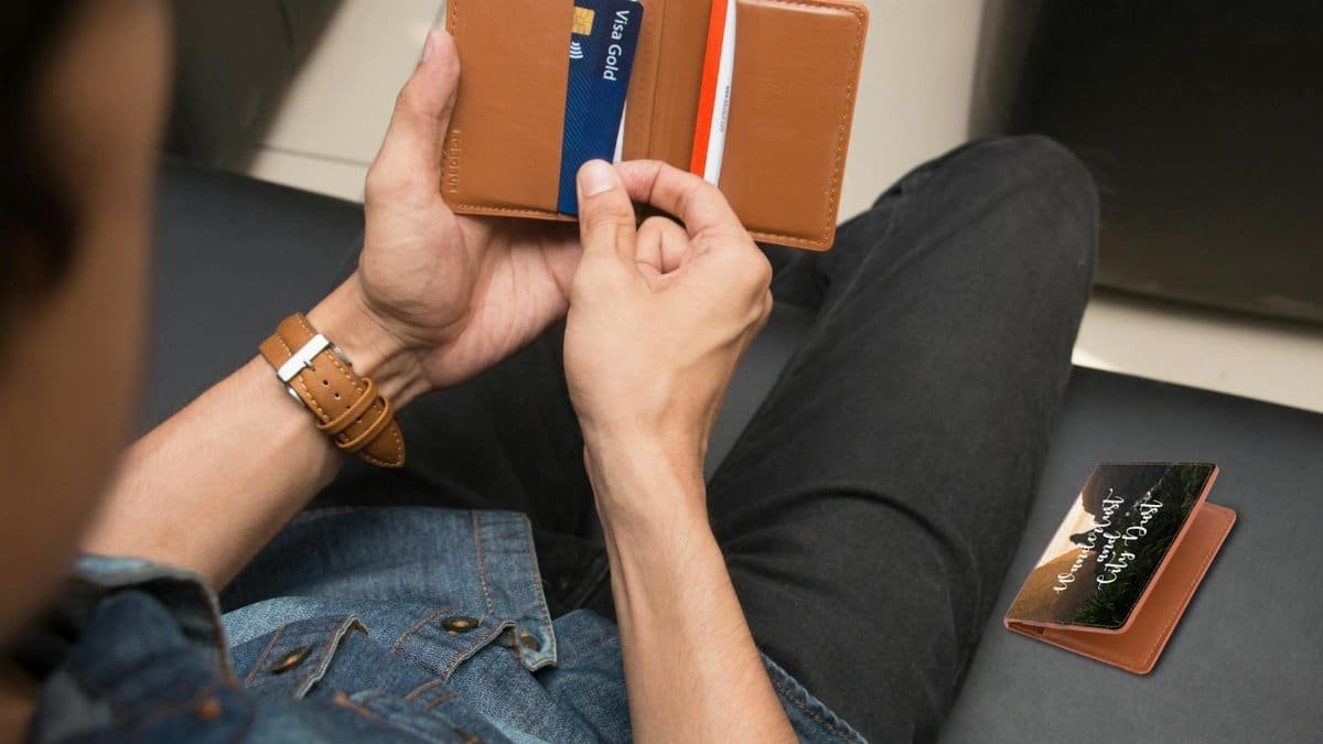 Over-the-shoulder view of a person holding a leather wallet displaying credit cards.