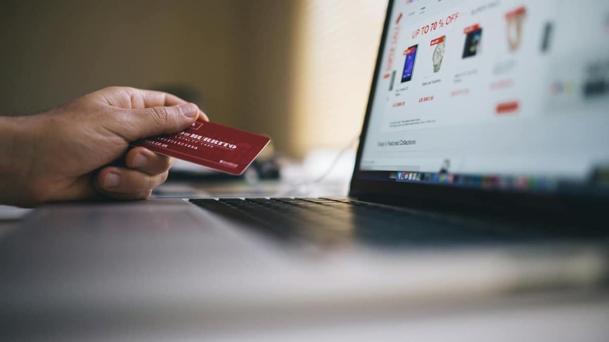 Person holding a credit card while shopping online on a laptop, indicating ecommerce transactions.