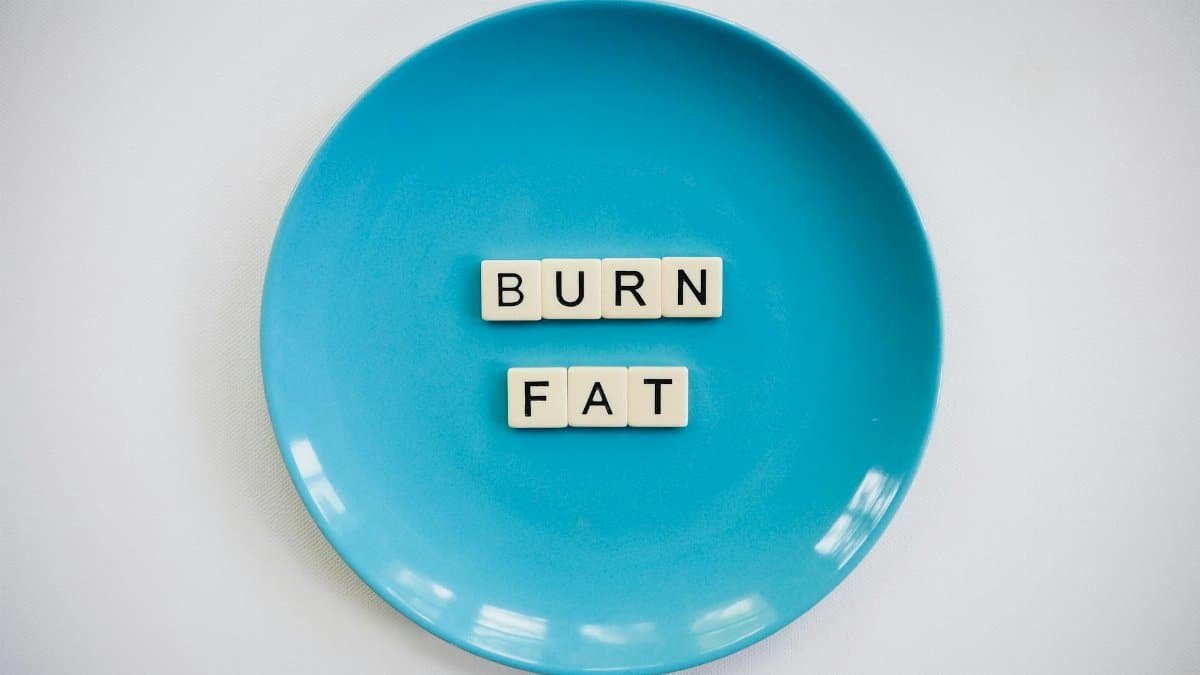 A conceptual image featuring the words 'Burn Fat' on a blue plate, symbolizing weight loss.