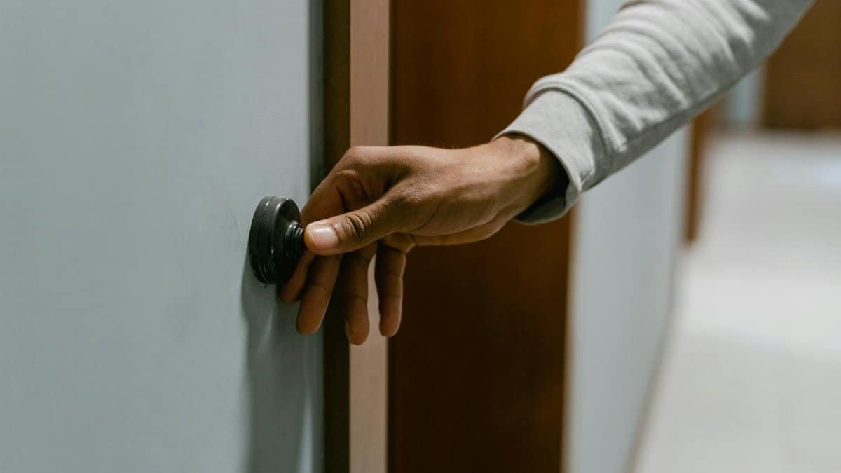 Close-up of a hand pressing a doorbell in an indoor setting, illustrating alert routines.