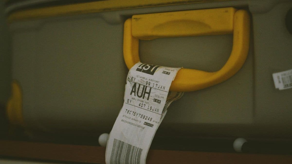 Close-up of a yellow suitcase handle with a visible travel tag and barcode, ideal for travel themes.