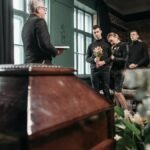 Attendees pay final respects at a solemn funeral ceremony indoors.