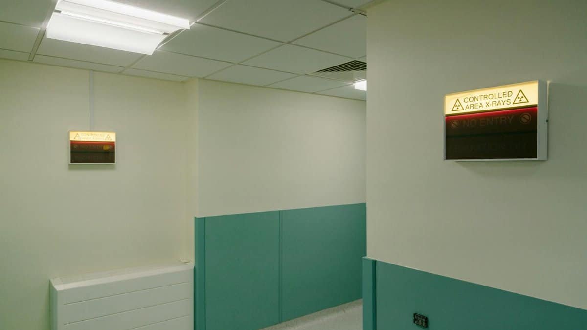 Interior hospital hallway with illuminated X-Ray area warning signs.
