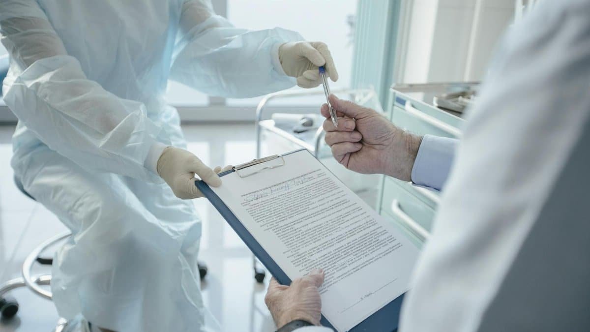 A doctor hands a clipboard to a patient for signature, highlighting medical professionalism.