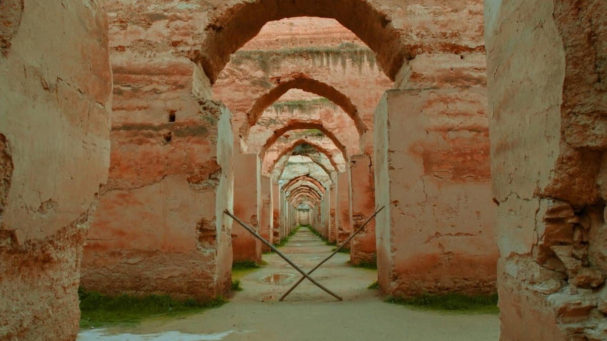 Explore an ancient arched corridor with historical stone walls and a tranquil ambiance.