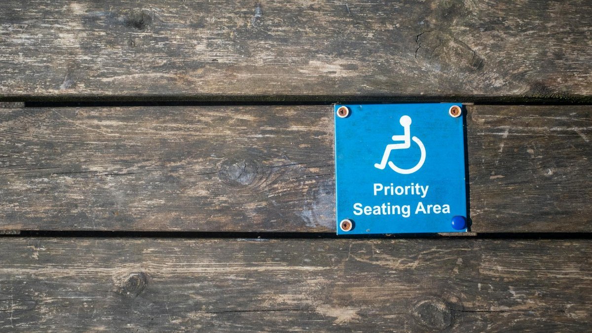 Close-up of a priority seating area sign with wheelchair symbol on a wooden surface.