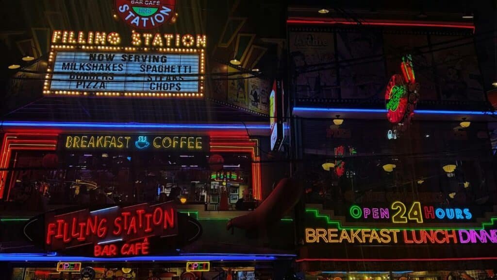 Neon signs of Filling Station Bar Cafe showcasing 24-hour service, breakfast, and coffee.