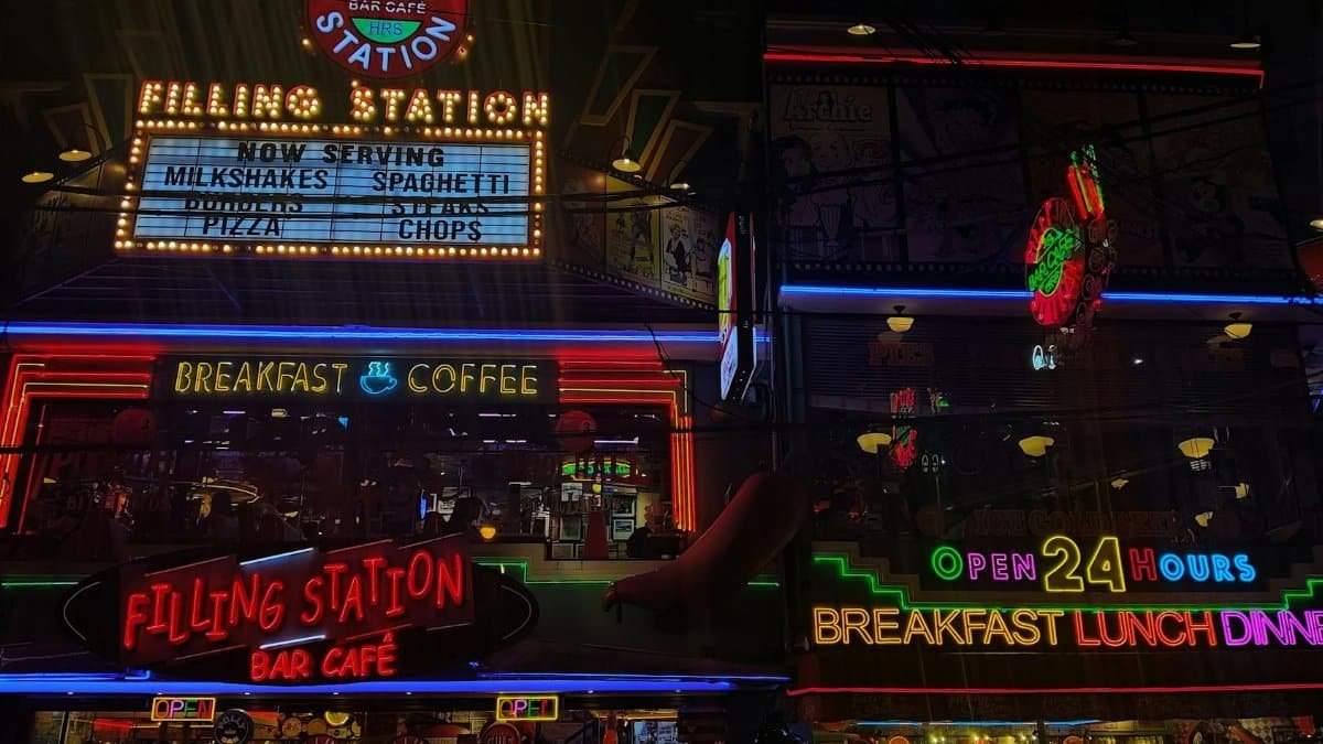 Neon signs of Filling Station Bar Cafe showcasing 24-hour service, breakfast, and coffee.