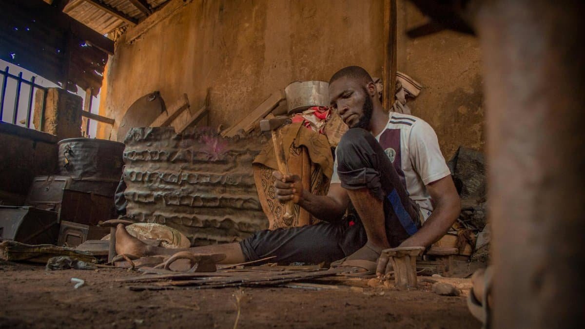 A focused craftsman works meticulously in a rustic, handcrafted workshop. Dusty and warm ambiance.