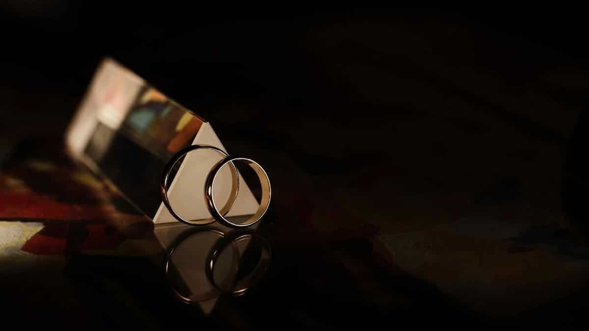 Close-up of wedding rings with a prismatic reflection against a dark background.