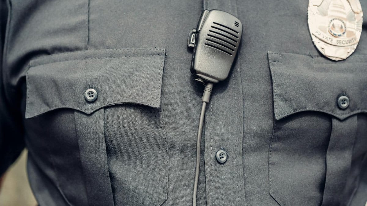 Close-up of a police officer's uniform featuring a body camera and badge.