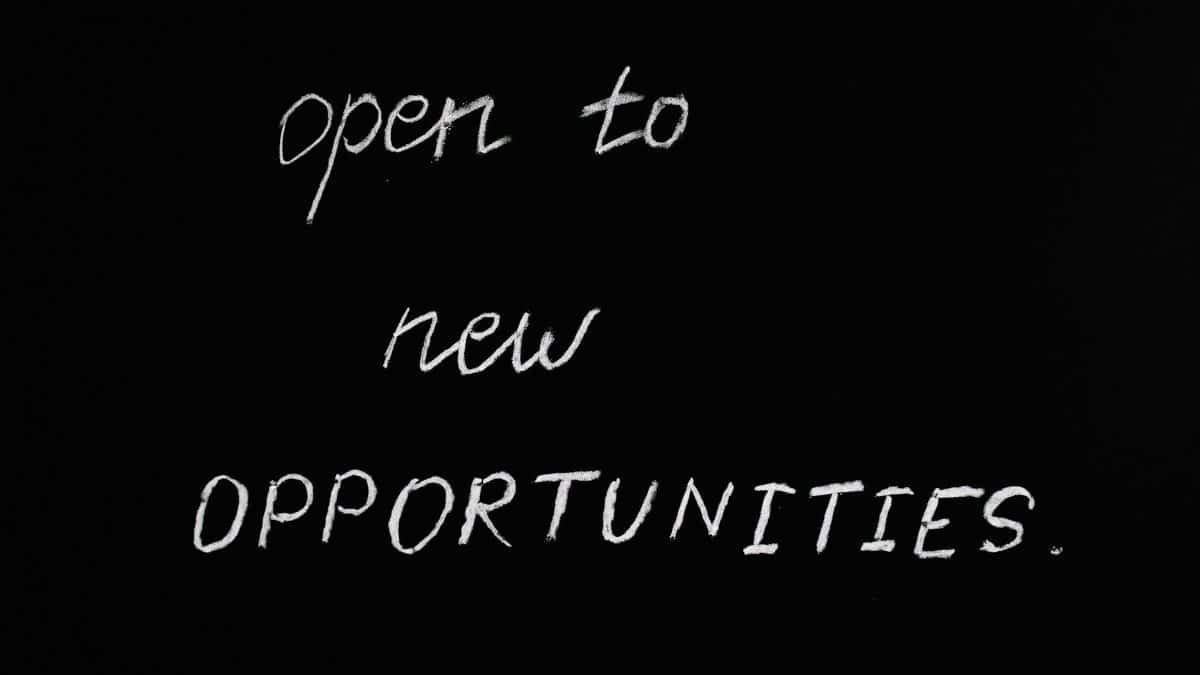 Blackboard with motivational quote 'Open to New Opportunities' in chalk writing.