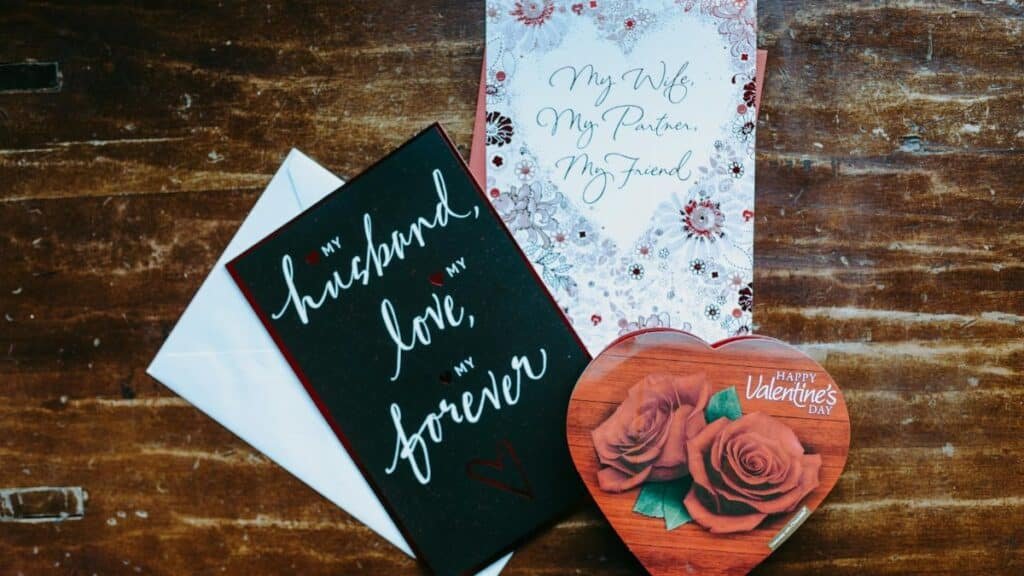 Heartfelt Valentine's Day cards and a heart-shaped chocolate box on a wooden surface, perfect for a romantic gift.