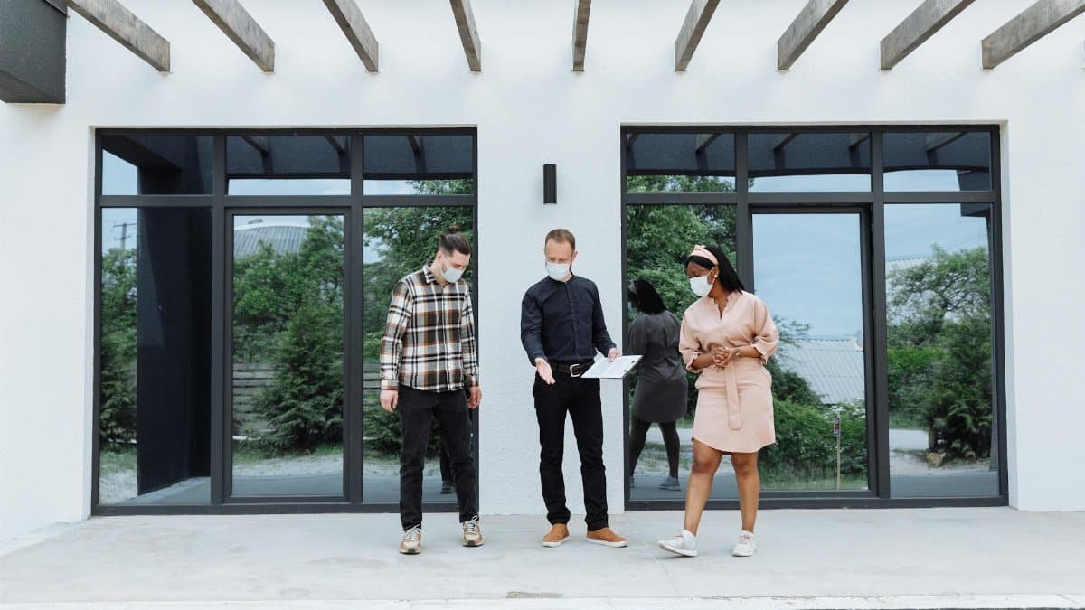 Real estate agents showing a house while maintaining safety protocols with face masks.