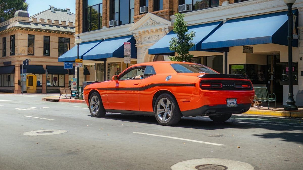 Vibrant orange Dodge Challenger parked on a sunny street in San Luis Obispo.
