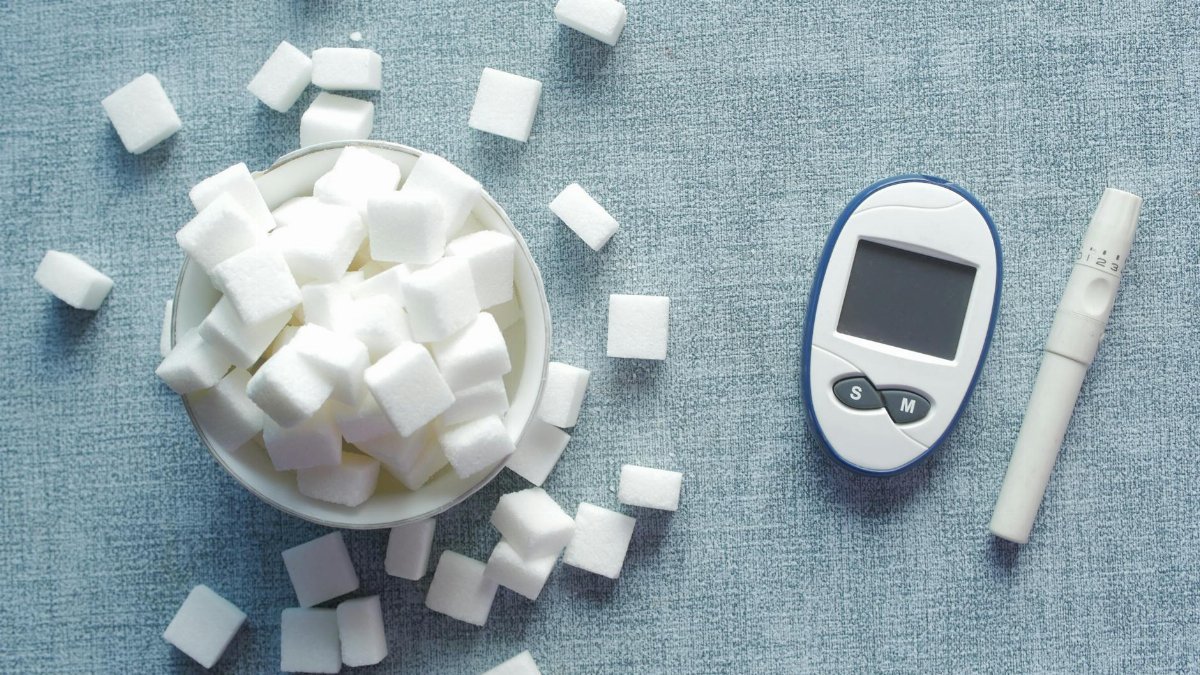 Overhead shot of a glucometer and sugar cubes representing diabetes management and sugar intake.
