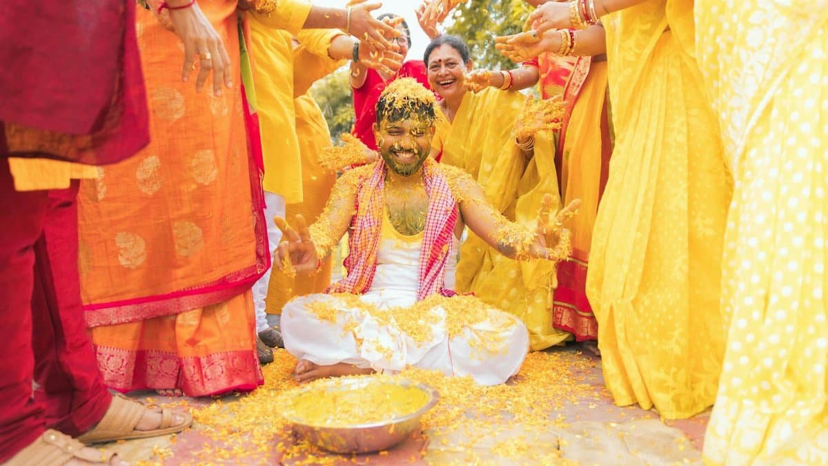 Colorful celebration with smiling groom during Indian pre-wedding ritual.