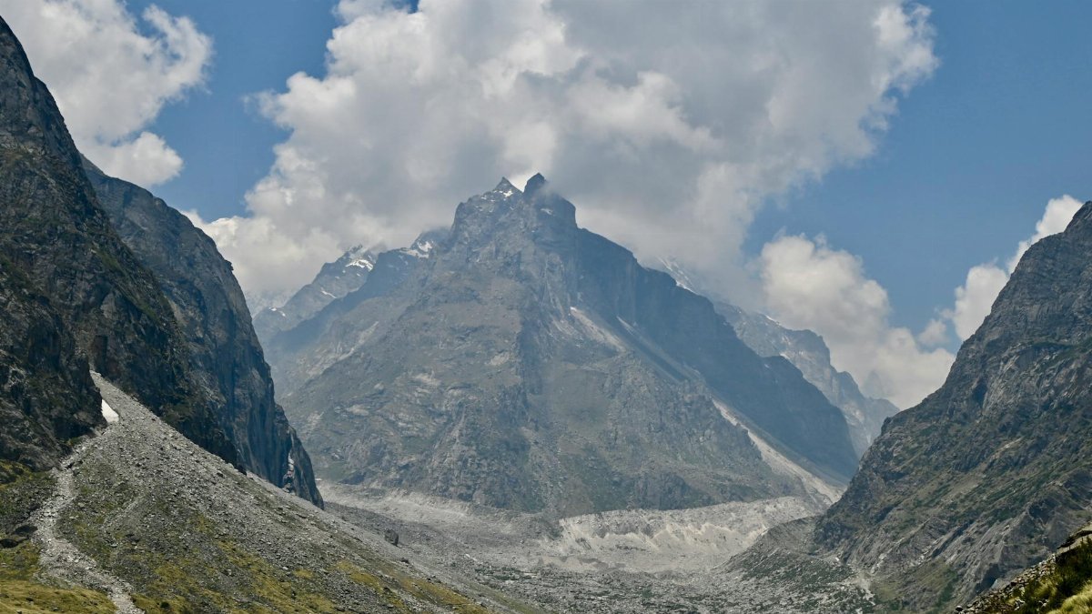 Explore the majestic mountains and valleys of Mana with clear blue skies and rocky terrains.