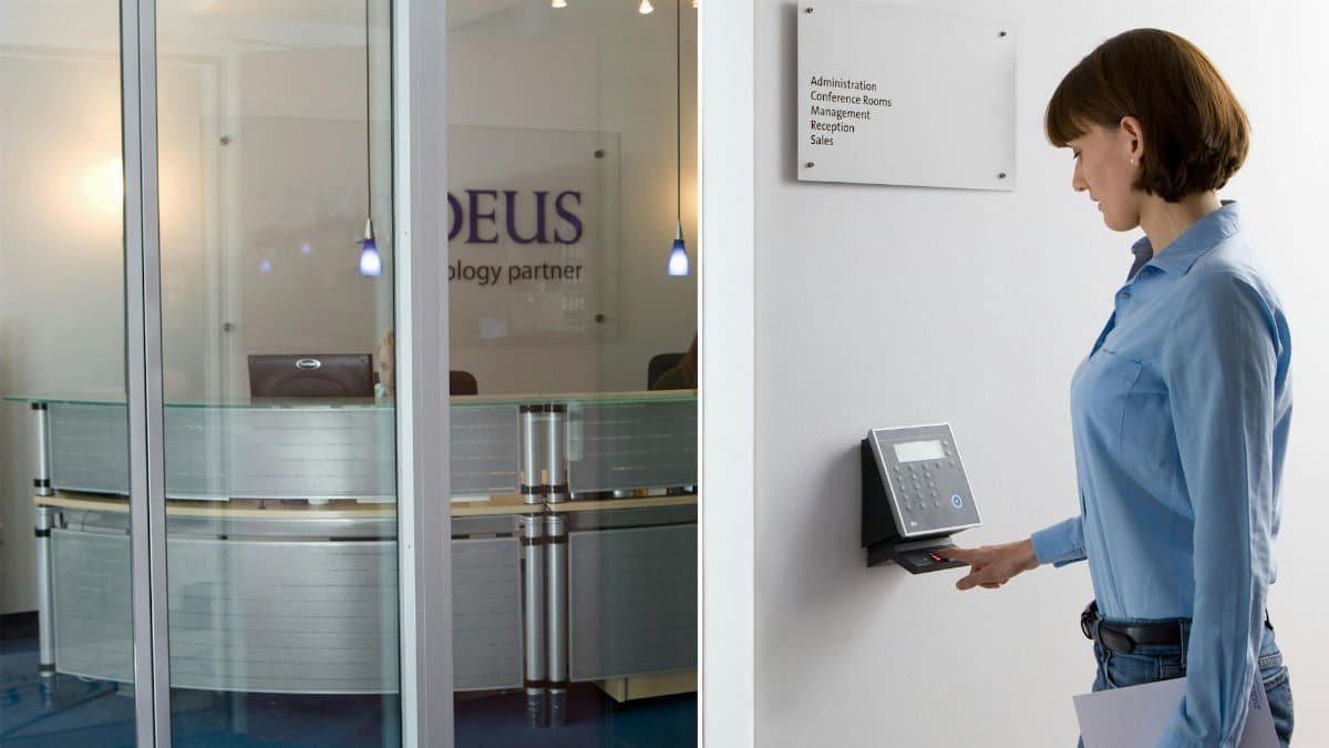 Woman using biometric scanner in modern office setting for access control.
