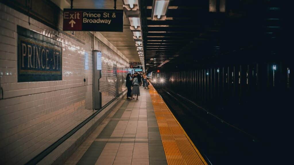 People waiting at Prince St subway platform in New York City, serene evening scene.