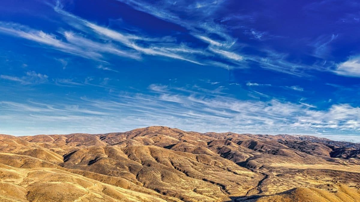 Breathtaking aerial view of Huntington's rolling desert hills under a vibrant blue sky in Oregon, USA.