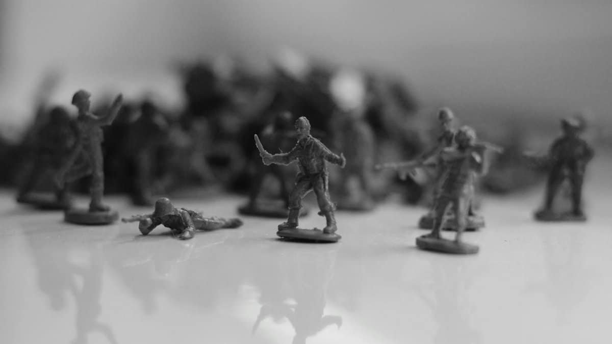 Black and white image of toy soldiers arranged in a dramatic battle pose on a reflective surface.