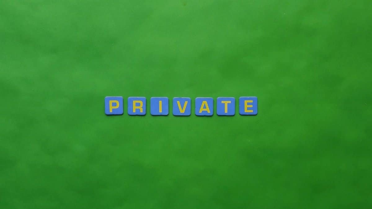 Close-up of 'PRIVATE' spelled with Scrabble tiles on a green background, emphasizing privacy.