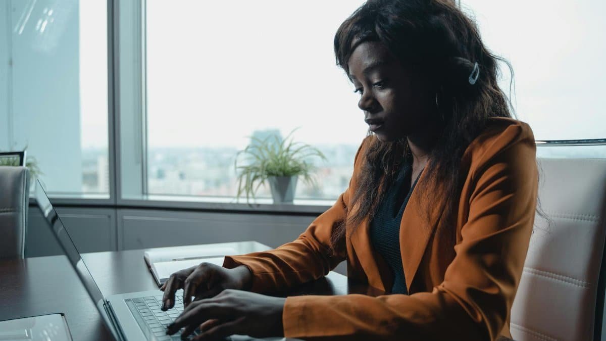 African American woman typing on laptop in a modern office setting.