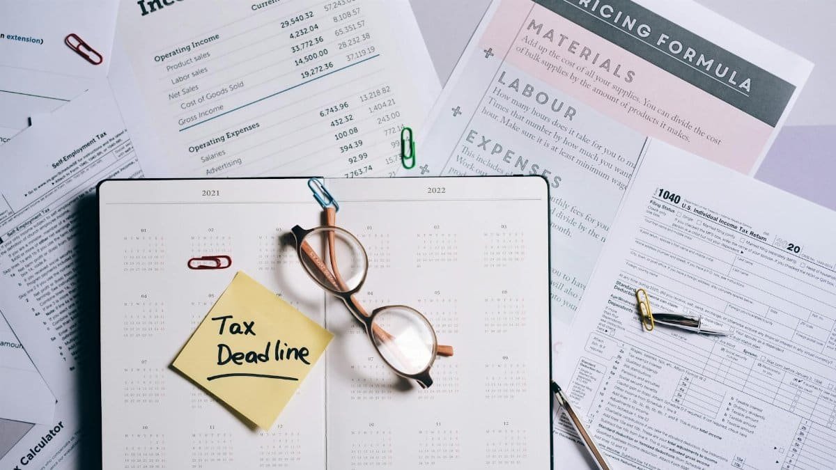 Overhead view of financial documents, planner, and glasses emphasizing tax deadline.