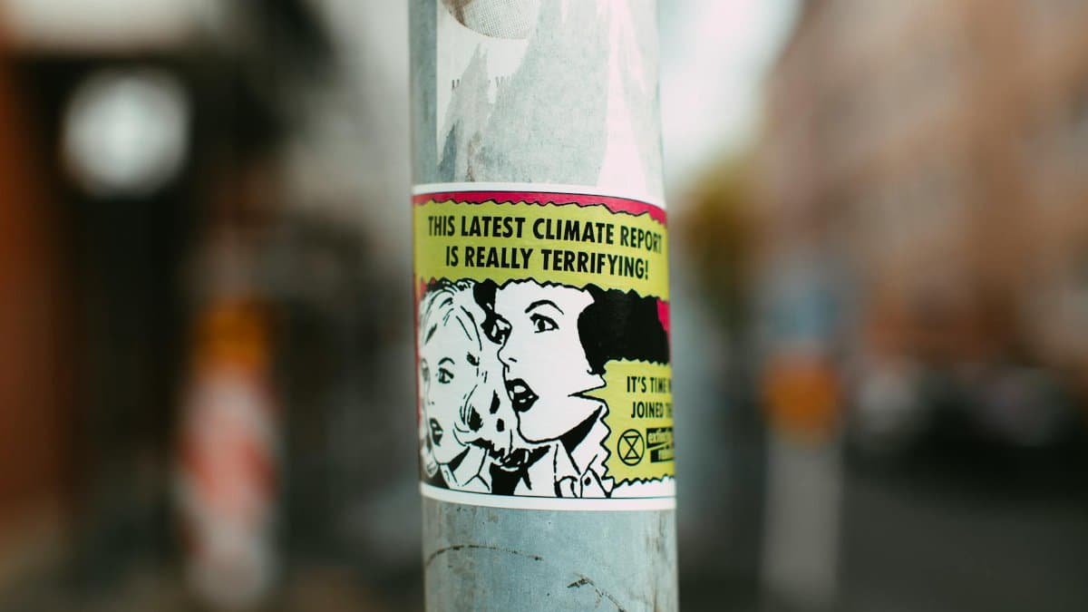 Sticker on pole with comic-style graphics raising awareness about climate change.