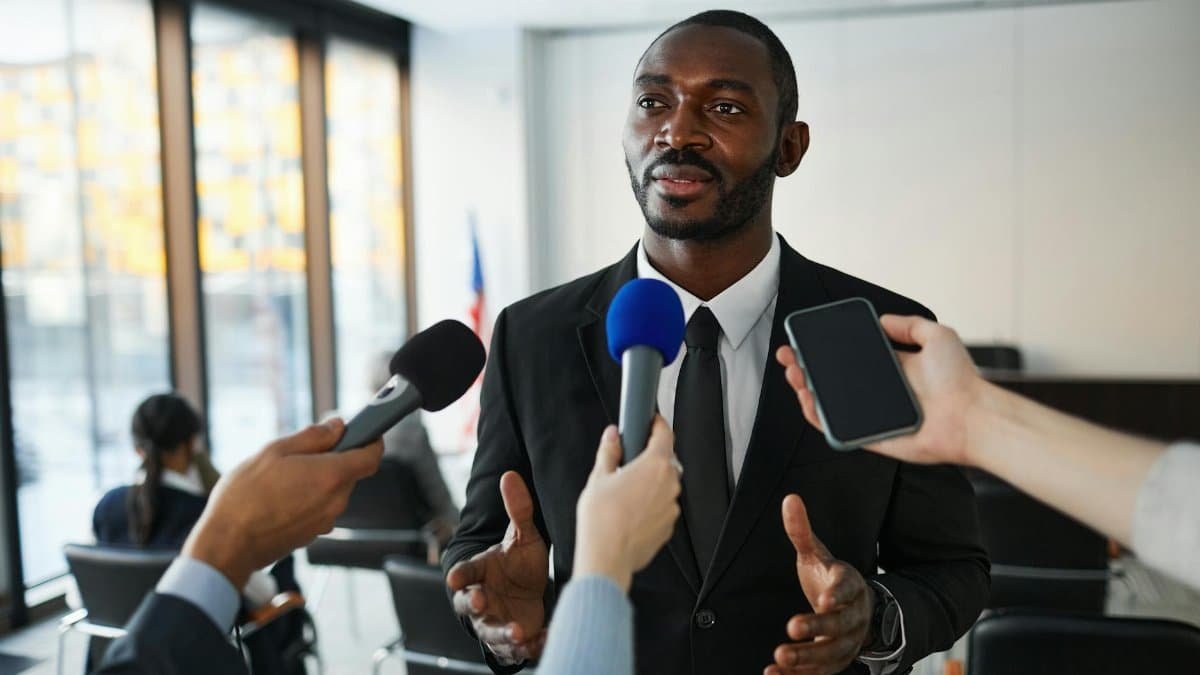Confident businessman answering questions from the media during a press conference indoors.